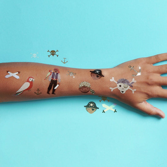 Leuchtendes Piraten-Tattoo auf dem Oberarm eines Kindes in einer dunklen Umgebung.